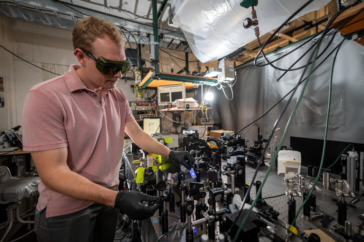 <p>Shane Devlin makes adjustments to the deep UV second harmonic generation spectroscopy device at UC Berkeley. (Credit: Thor Swift/Berkeley Lab)</p>

