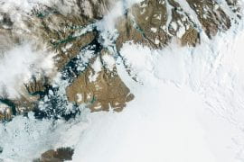<p>In the center of this NASA photograph taken in 2012, Petermann Glacier in northwest Greenland gradually moves toward the ocean, with large segments breaking off and drifting away as icebergs. Researchers at UCI and NASA JPL used satellite data from three European missions to learn how warm ocean water is causing the migration of the glacier’s grounding line, leading to its rapid deterioration. NASA</p>
